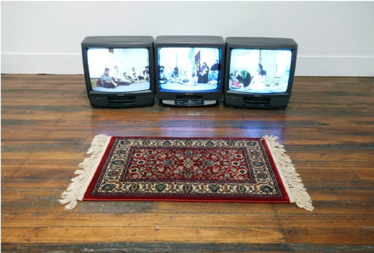 Three small televisions sit on the floor with a carpet.