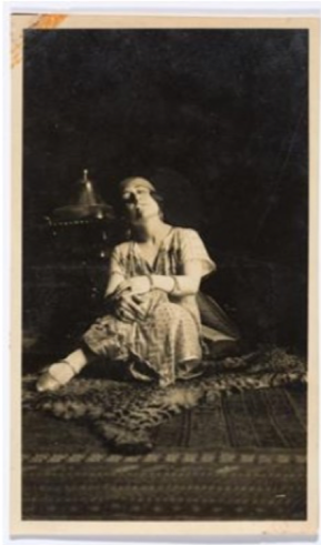 A woman seated on the floor and wearing a costume