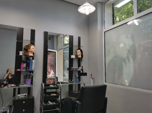 A hairstyling station with a chair, hairstyling tools, and model heads