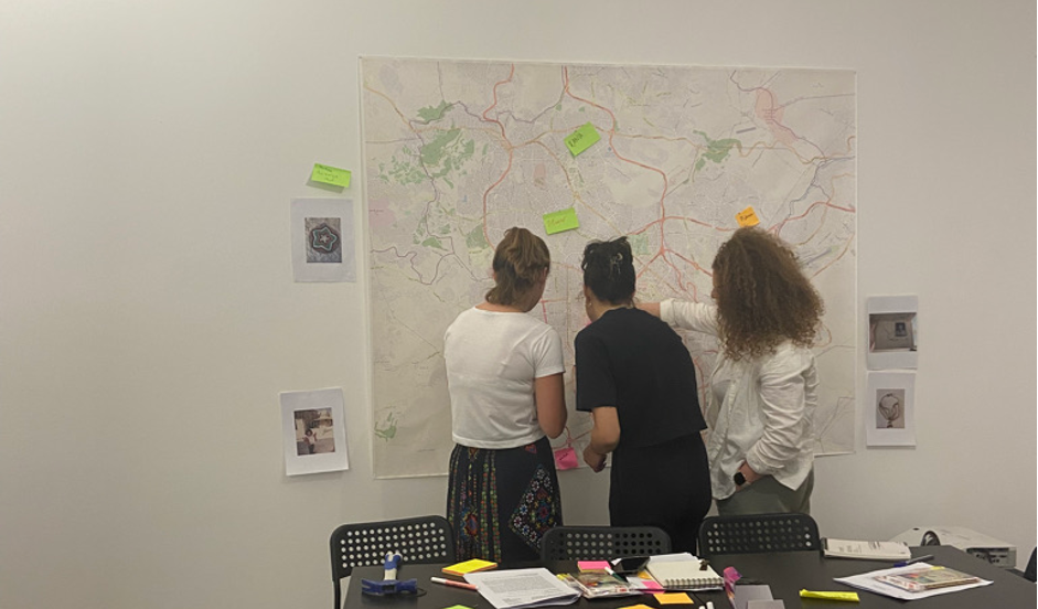 Three workshop participants study a map of Amman.